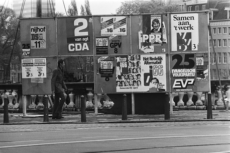 Een zwartwit foto van een plakbord met verkiezingsposters voor de Tweede Kamerverkiezingen 1981. Onder meer VVD met "Samen aan 't werk" en D66 met "Het redelijk alternatief"