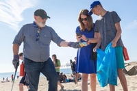 Frans Timmermans, on the left, picks up plastic trash on the beach.